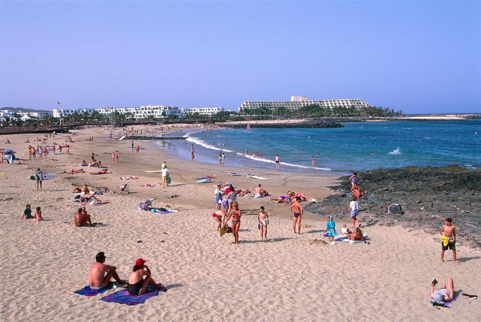 a beach scene with a hotel in the background