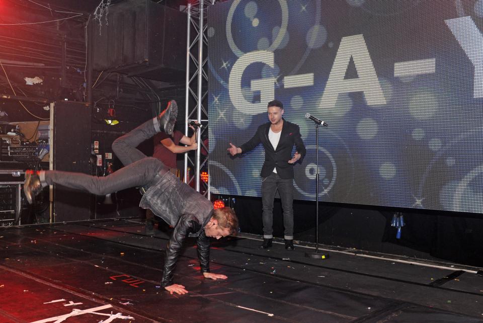 a man doing a handstand in front of a screen that says g-a-y