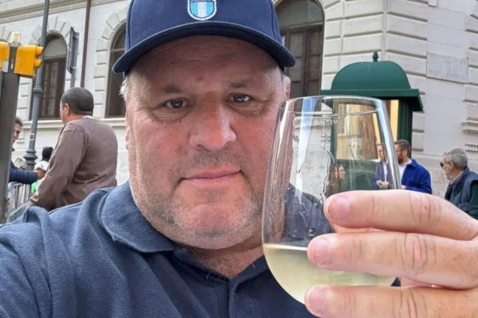 a man in a blue hat holds a glass of wine