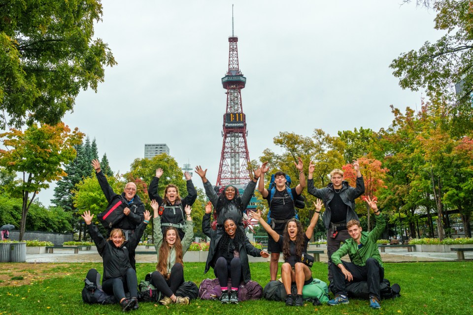a group of people posing in front of a panasonic tower