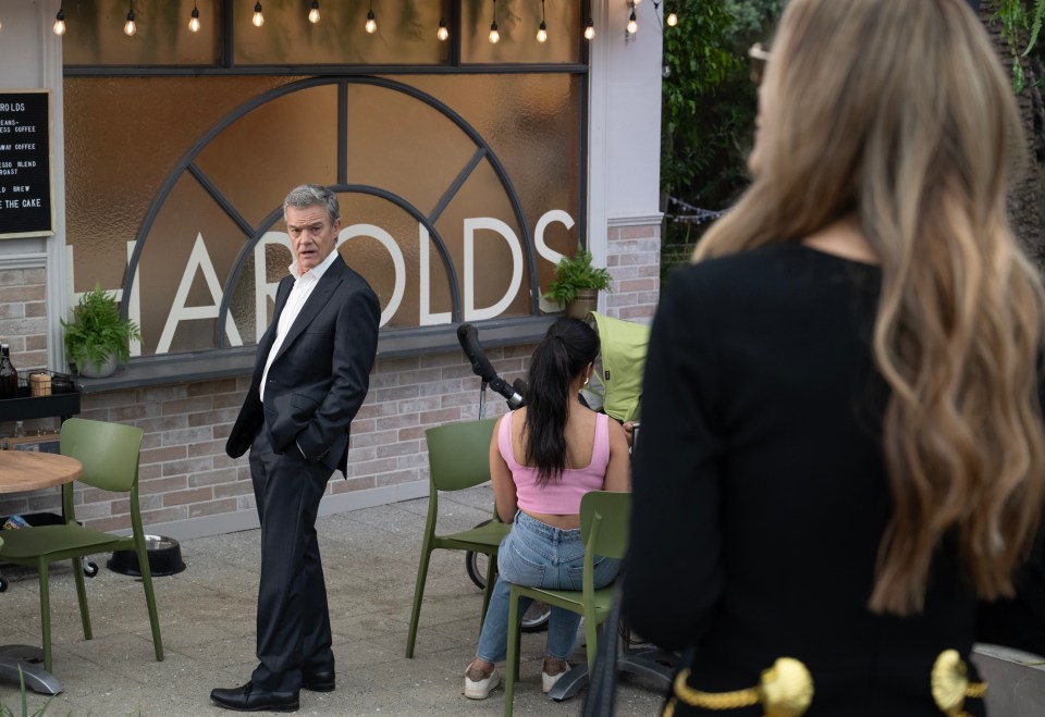 a man in a suit stands in front of a sign that says arolds
