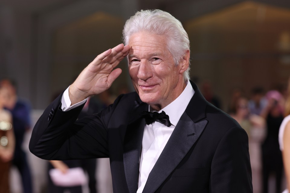 a man in a tuxedo salutes with his hand on his forehead