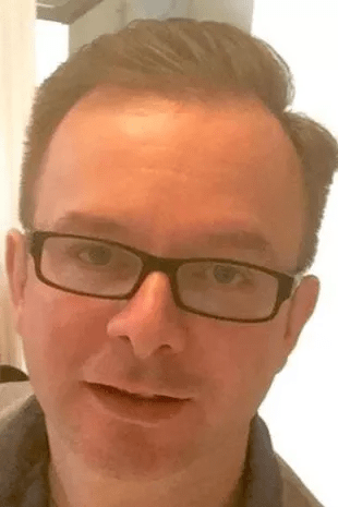 a close up of a man wearing glasses and smiling .