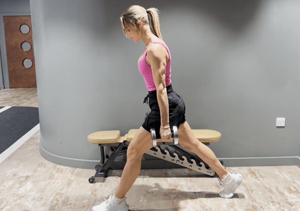 a woman in a pink tank top is holding a dumbbell