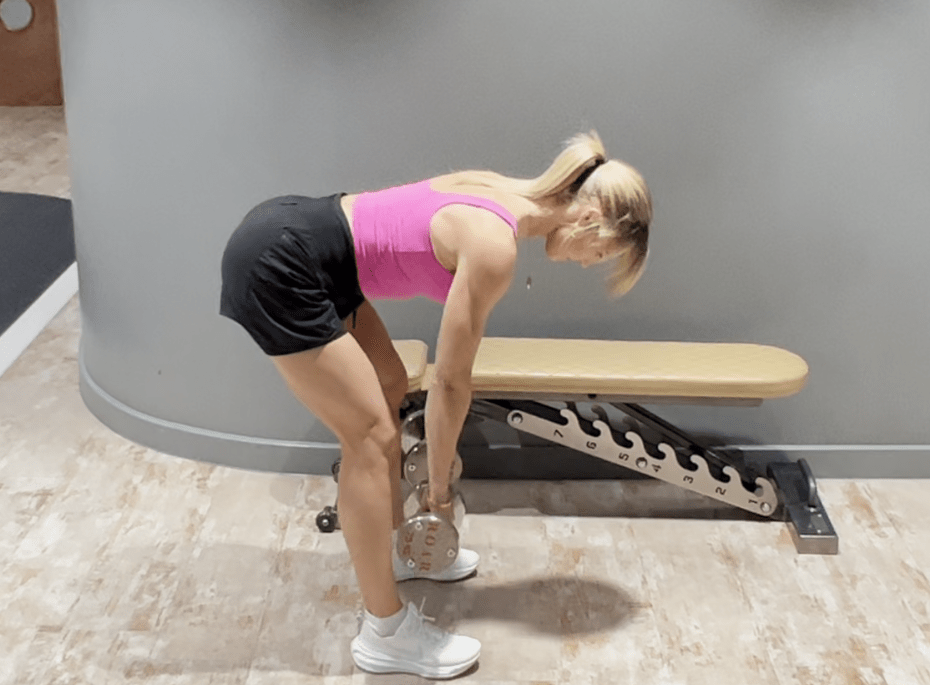 a woman in a pink tank top is lifting a dumbbell