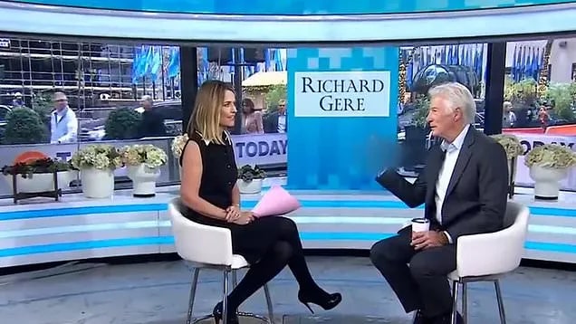 a man and a woman are sitting in chairs on a stage talking to each other .