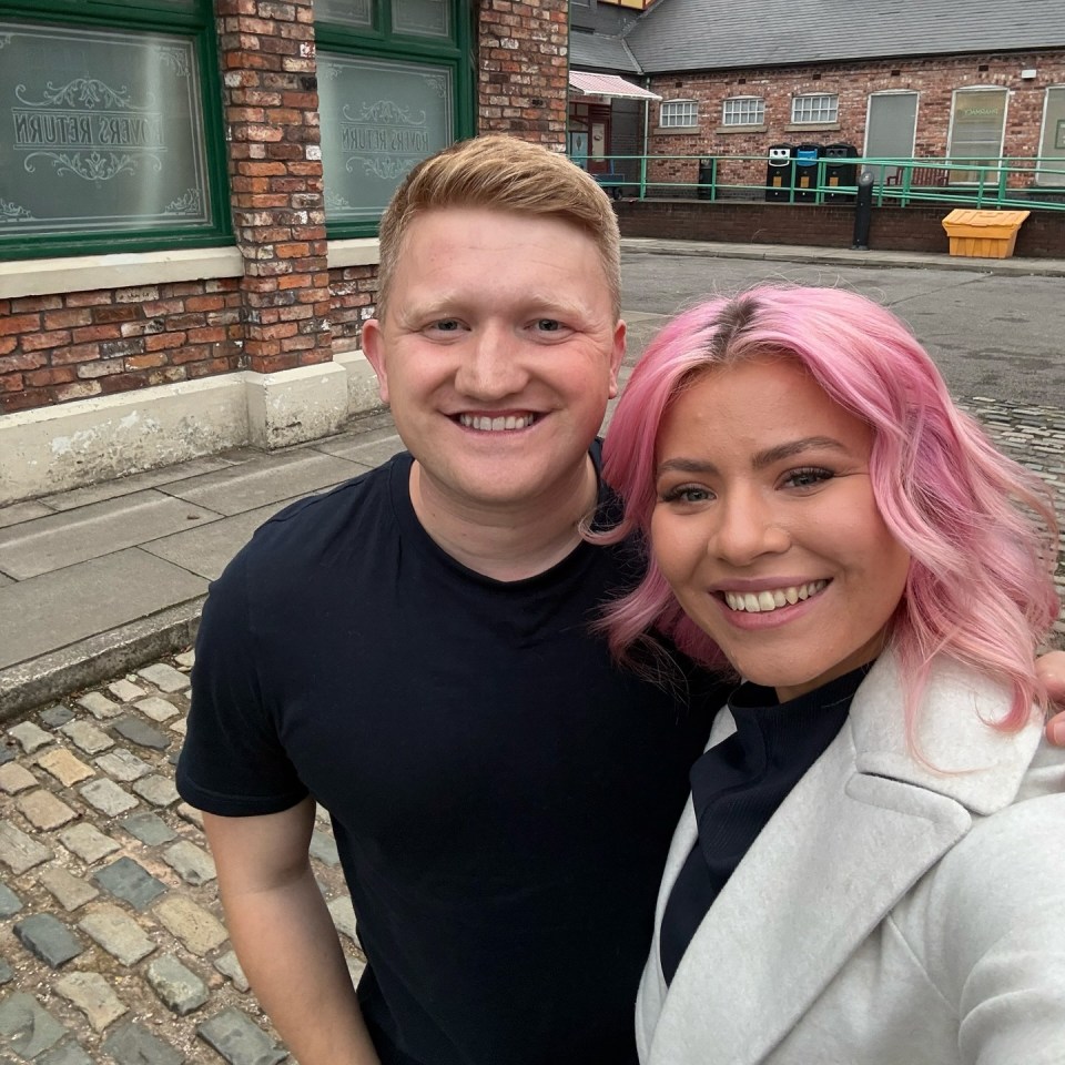 a man and a woman are posing for a picture in front of a building that says ' william smith ' on it
