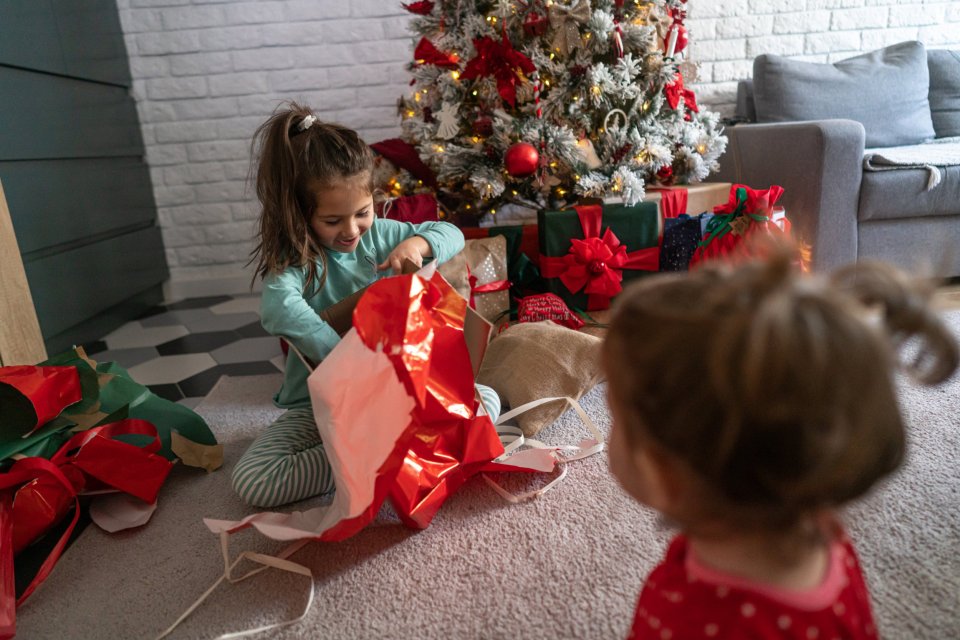Two sisters open Christmas presents on Christmas morning.
