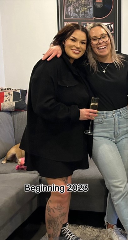 Two women pose for a photo, one holding a champagne flute.