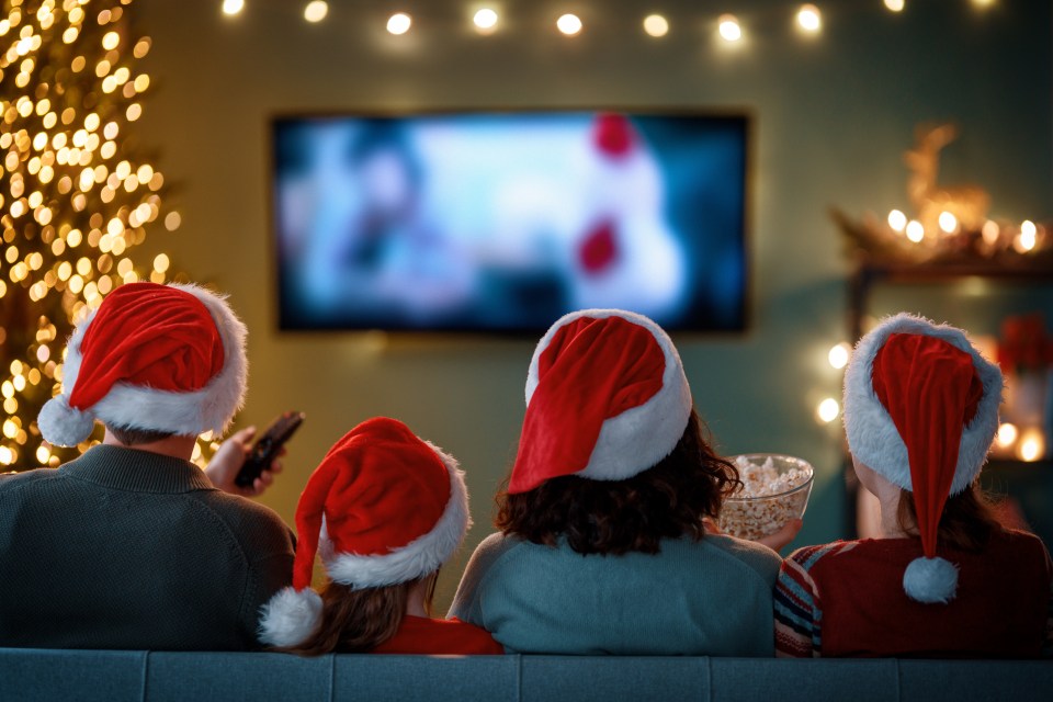 Family in Santa hats watching a movie on Christmas.