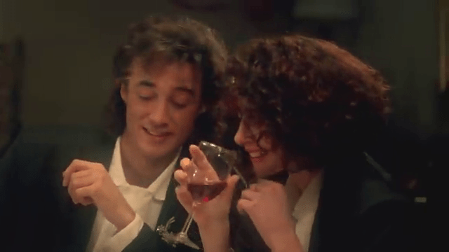 A man and woman share a glass of wine.