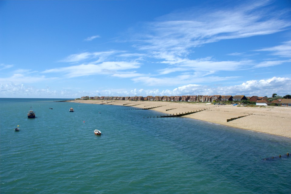 Selsey beach with houses and boats.