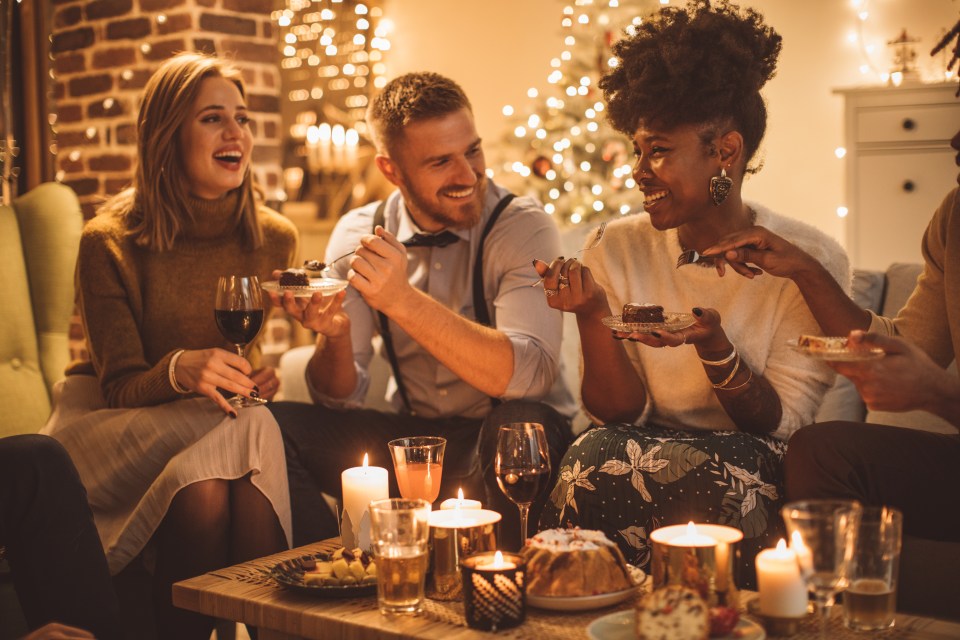 Friends enjoying a party at home, eating cake and drinking wine.