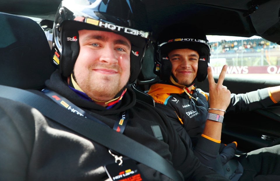 Lando Norris and another person in a car, wearing racing helmets.