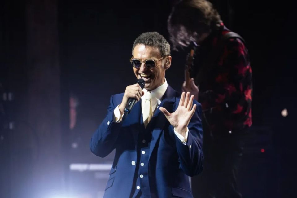 Man in suit singing into a microphone on stage.