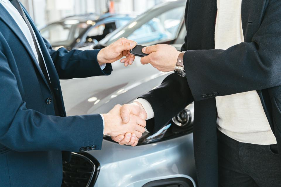 Two men shaking hands after a car sale.