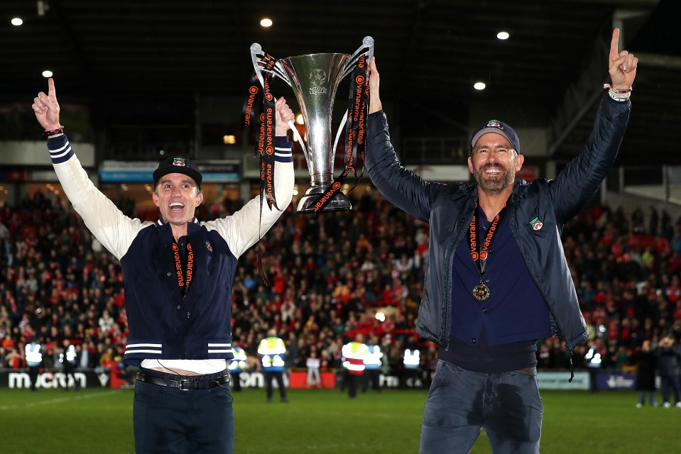 Rob McElhenney and Ryan Reynolds celebrating Wrexham's victory with the National League trophy.