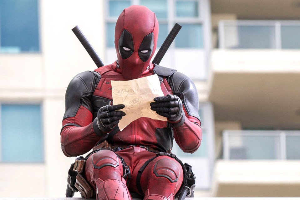 Deadpool examining a drawing.