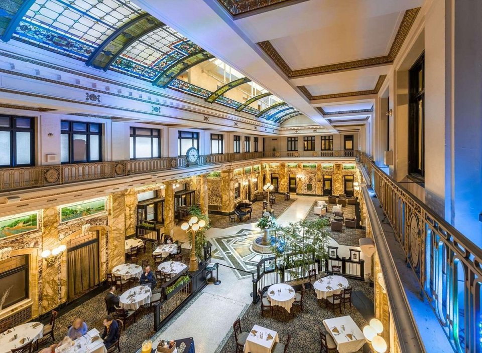 Interior view of the Radisson Lackawanna Station Hotel Scranton, showing a large atrium with a stained-glass ceiling, marble walls, and dining areas.