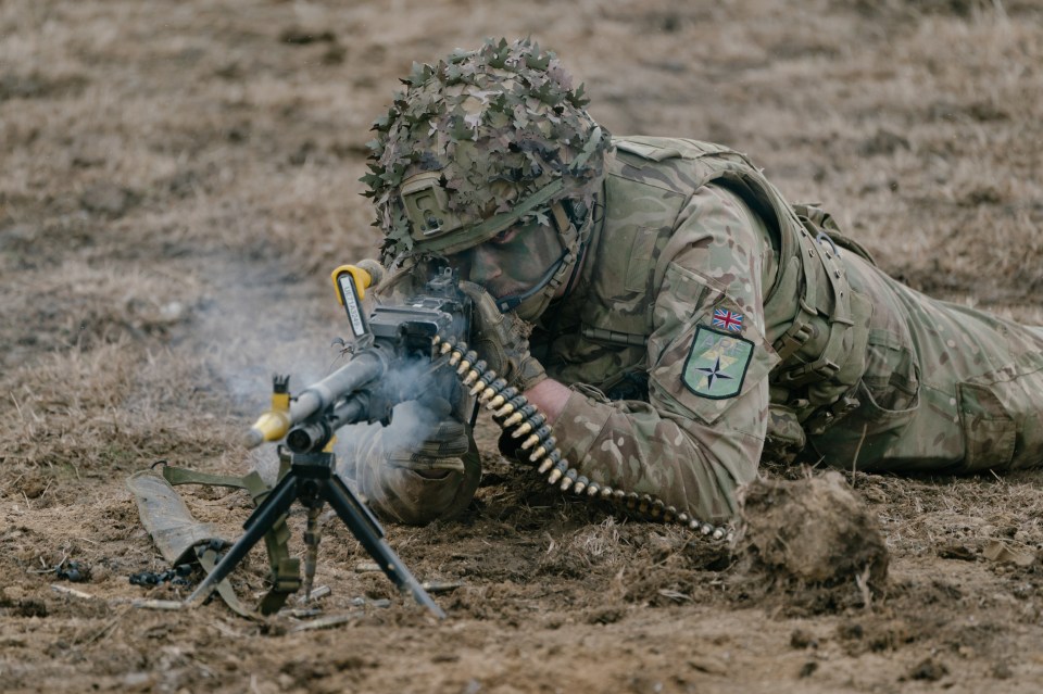 British soldier firing a machine gun during a NATO military exercise.