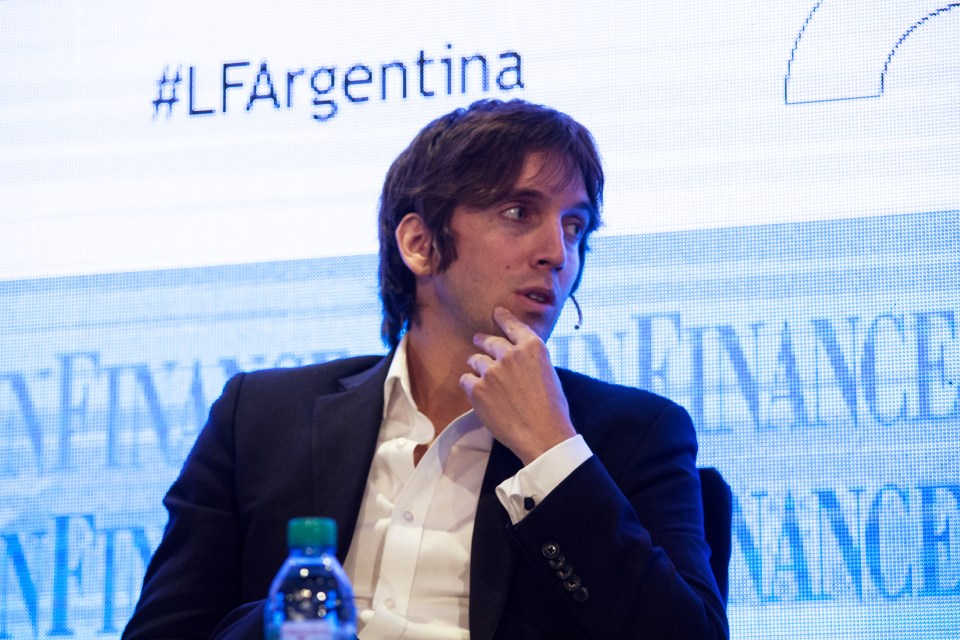 A man in a suit listens attentively at a financial summit.