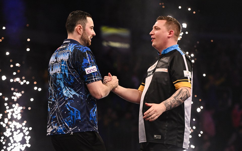 Luke Humphries and Chris Dobey shaking hands after a darts match.