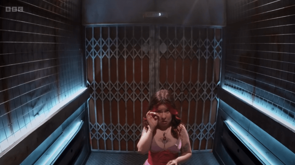 Woman in an elevator with metal gates.