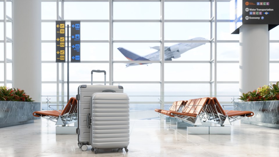 Empty airport waiting area with luggage and airplane in background.