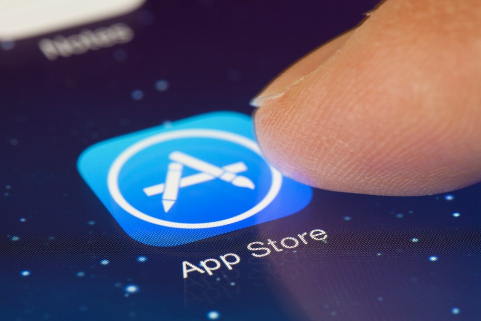 Finger touching App Store icon on an iPad screen.