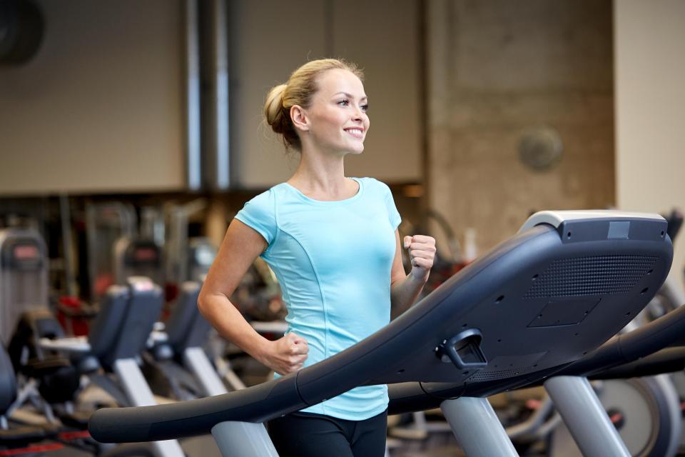 Woman smiling while exercising on a treadmill at the gym.