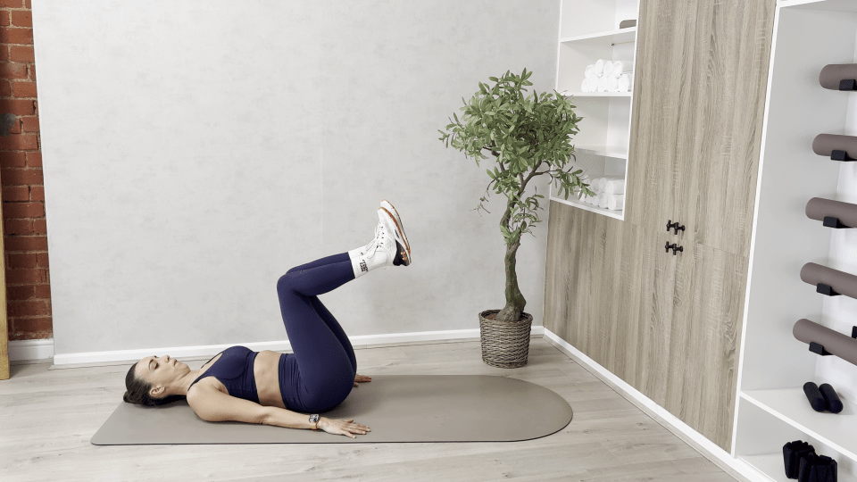 Woman doing a leg raise exercise on a yoga mat.
