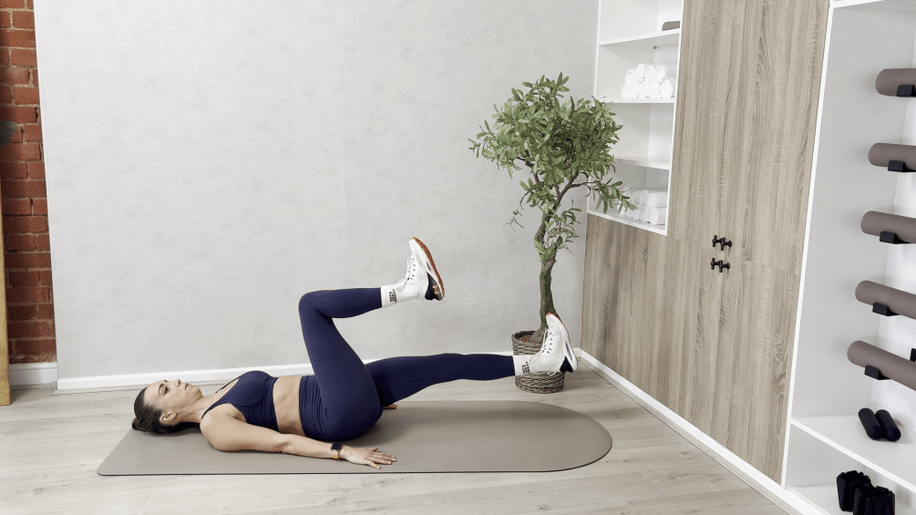 Woman performing a leg raise exercise on a mat.