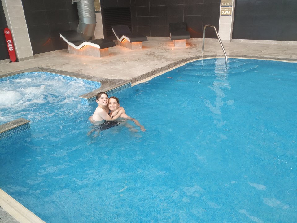 Two boys hugging in a resort pool.