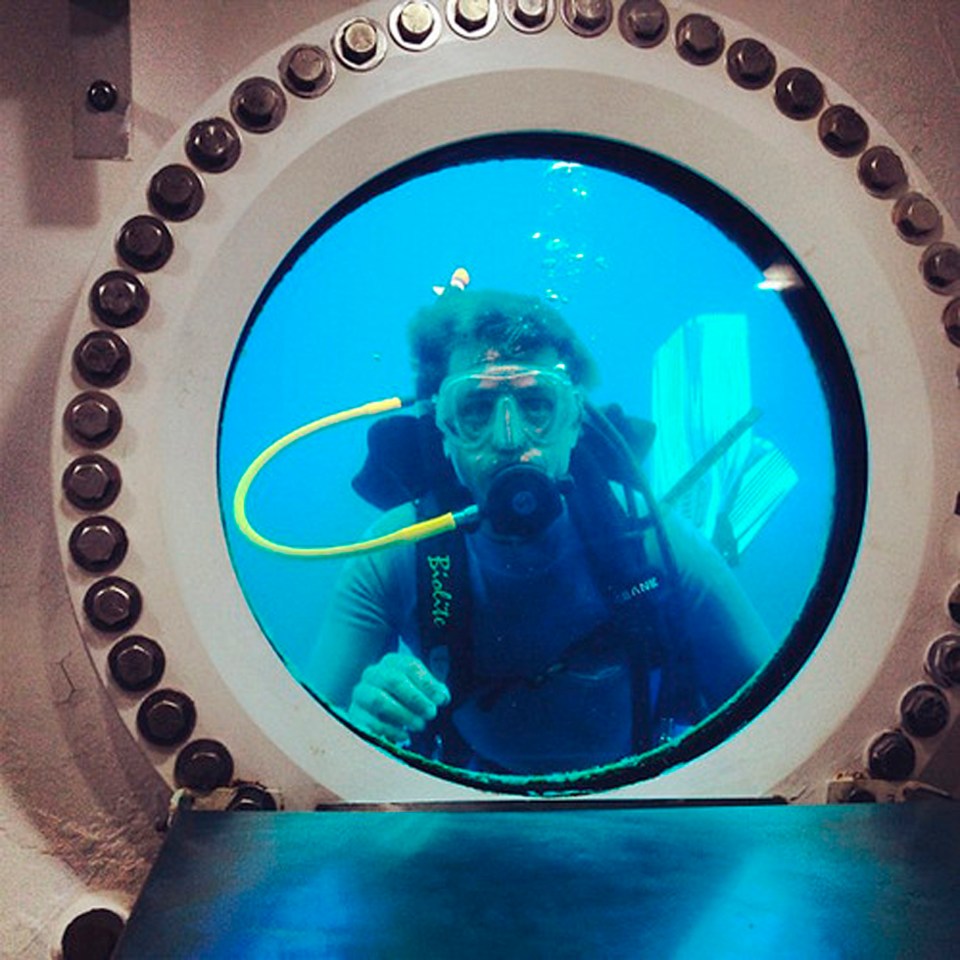 Diver viewed through underwater habitat porthole.