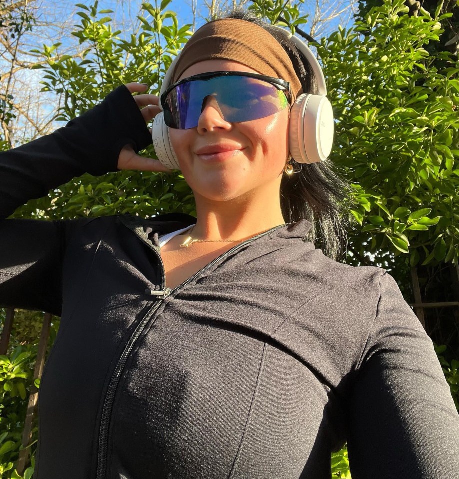 Woman wearing headphones and sunglasses outdoors.