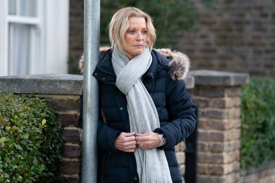 Kathy Beale from EastEnders standing outside.