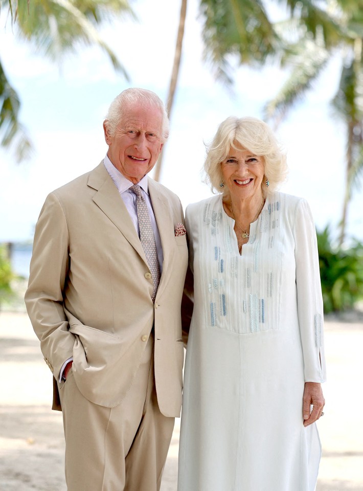 King Charles and Queen Camilla smiling on a beach.