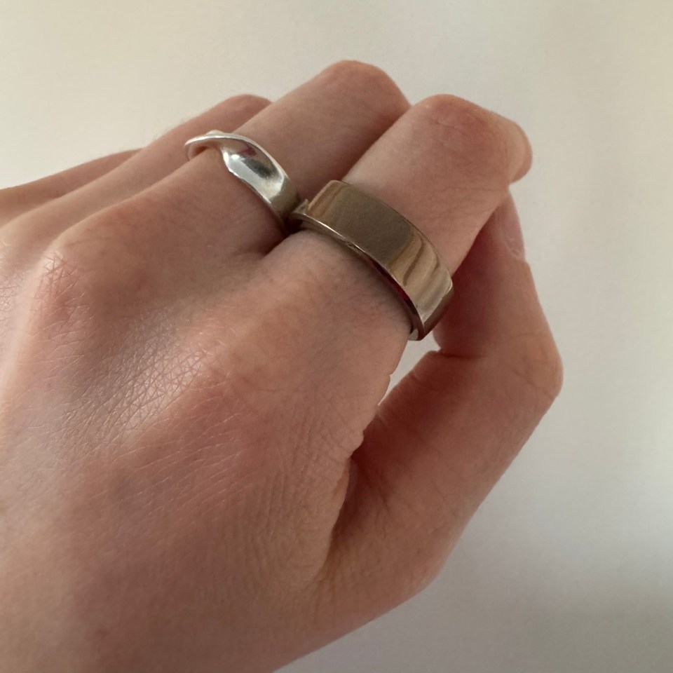 Person's hand wearing two rings.