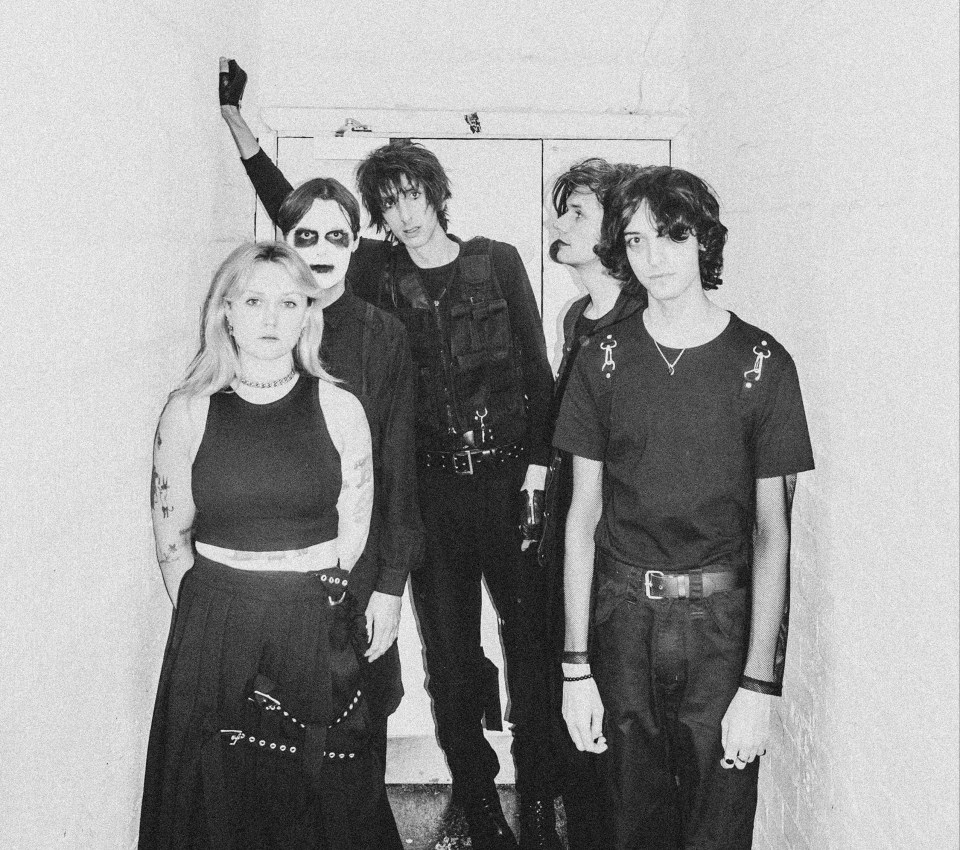 Black and white photo of a band posing in a hallway.