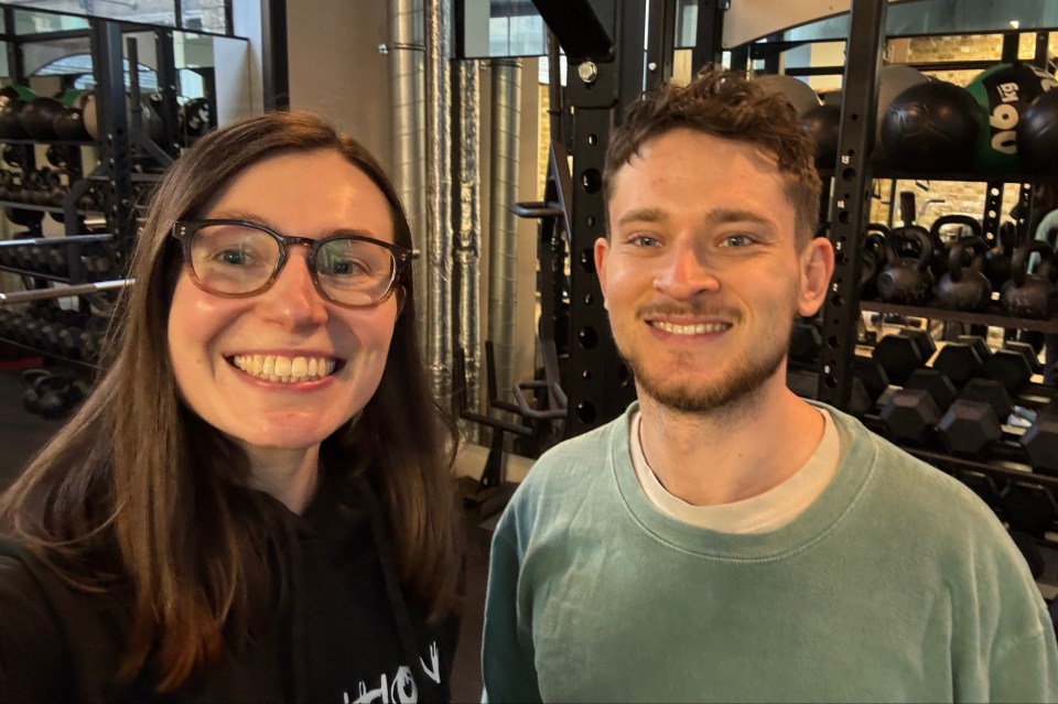 Two people smiling for a selfie in a gym.
