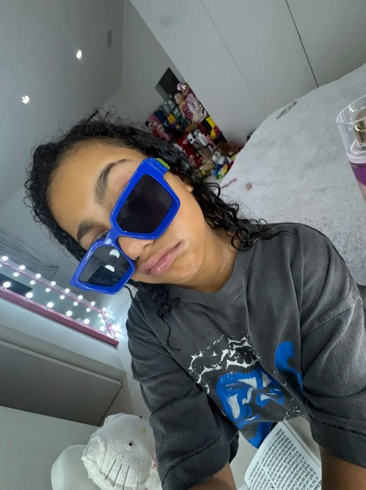 North West wearing blue sunglasses in her bedroom.