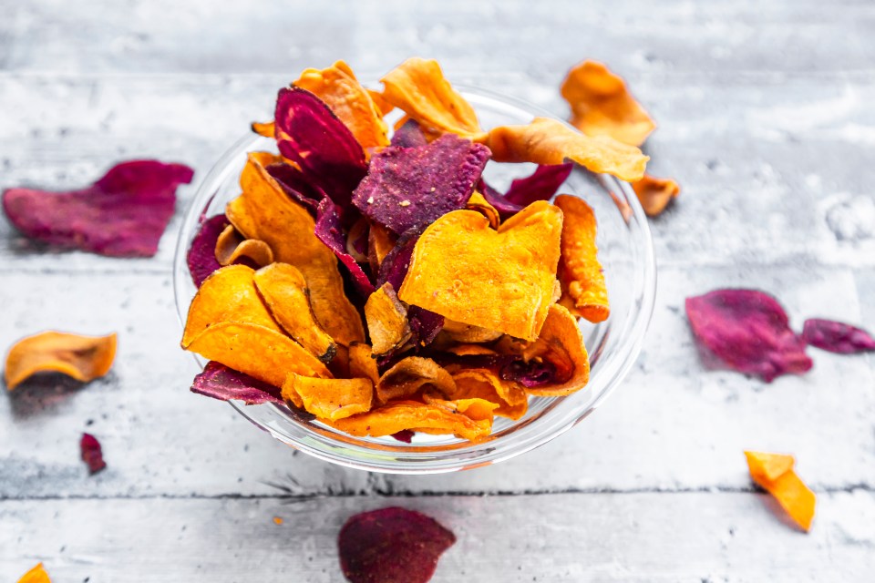 colourful roasted chips made of yellow and lila sweet potaoes and parsnips