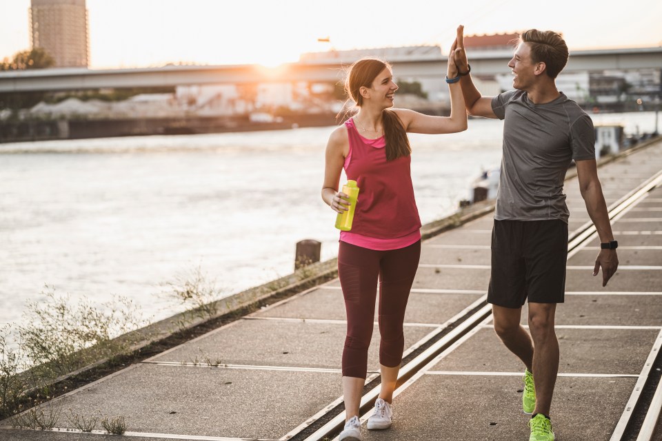 Young couple high-fiving after a workout by the water.