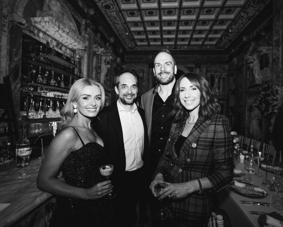 Black and white photo of four people at a bar.