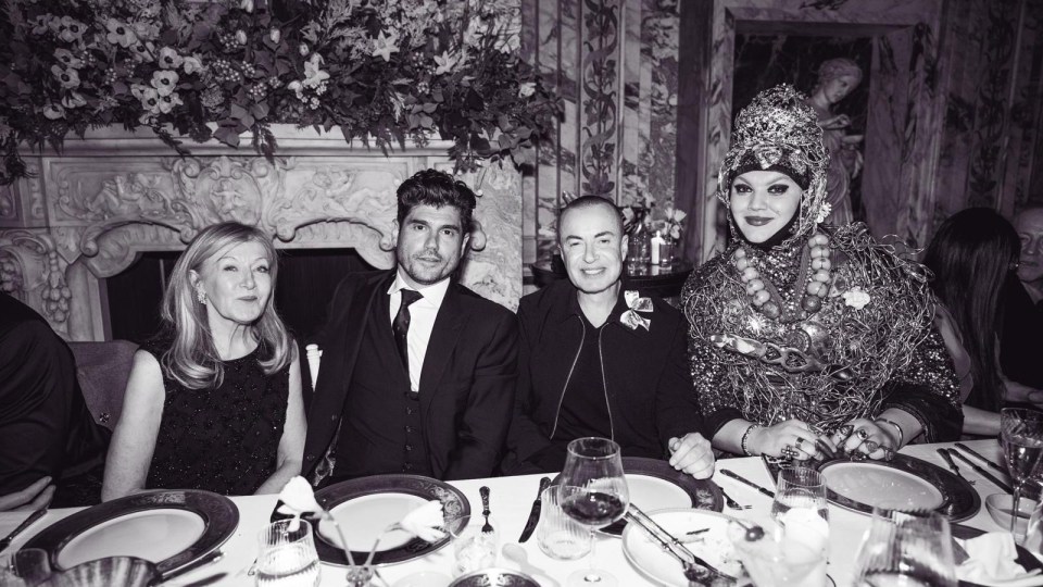 Black and white photo of four people sitting at a table.