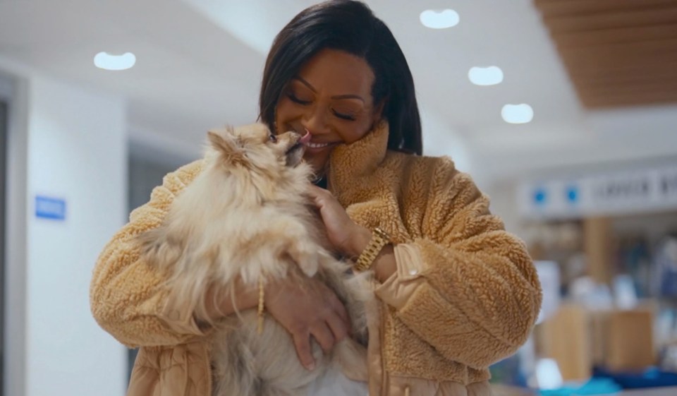 Alison Hammond holding and kissing a small dog.