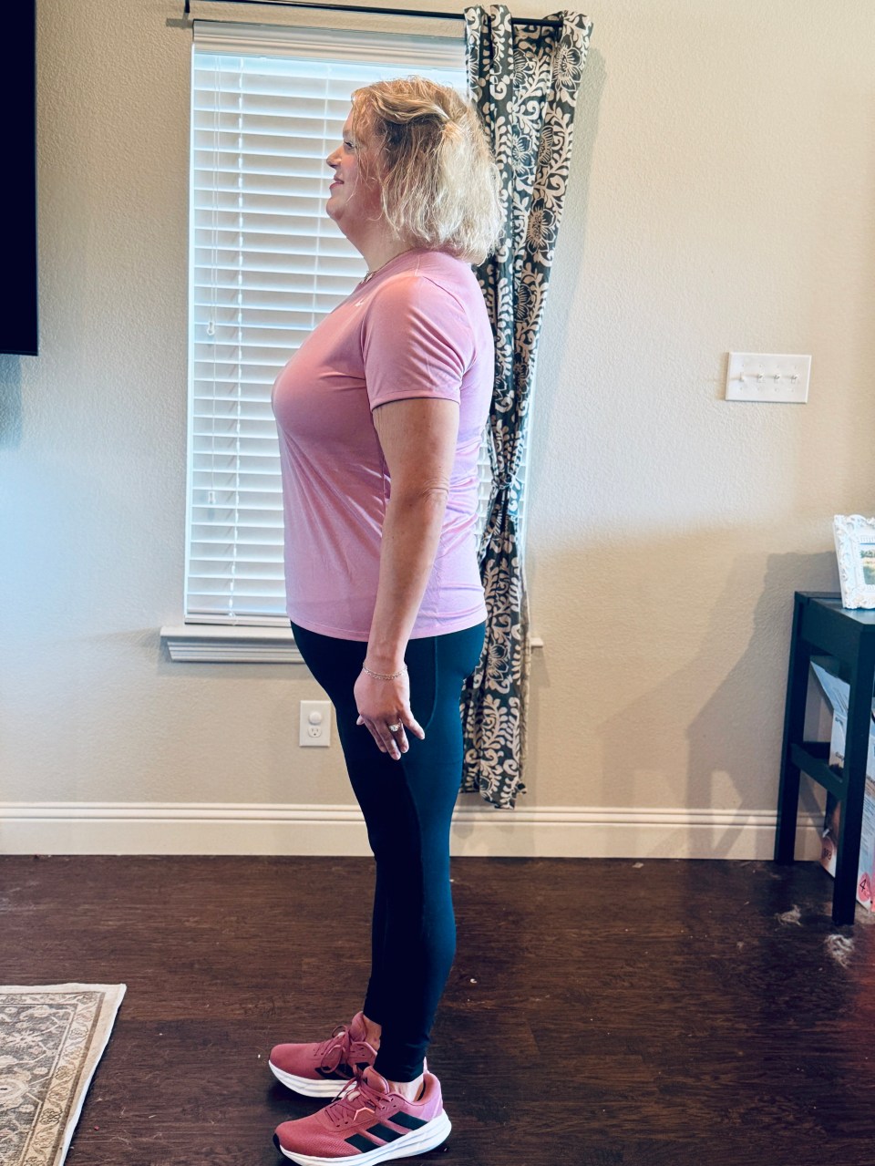 Woman in pink shirt and black leggings after weight loss.