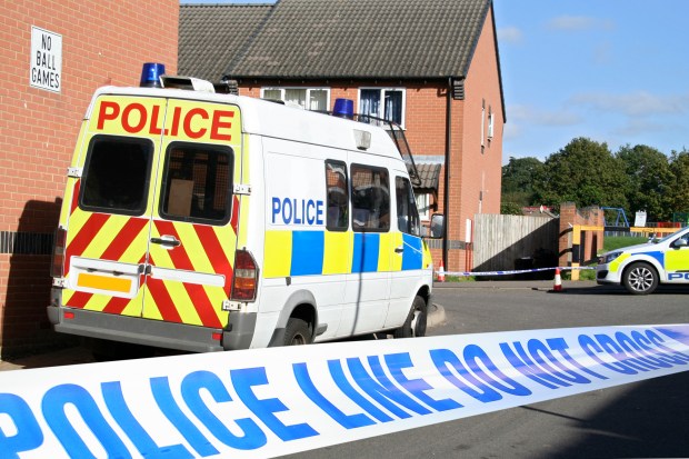 British police van and car at a cordoned-off crime scene.