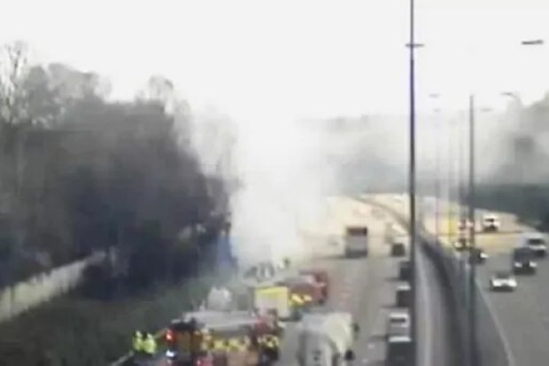 Smoke and emergency vehicles at a highway crash site.