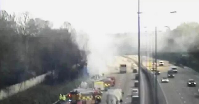 Smoke and emergency vehicles at a highway crash site.